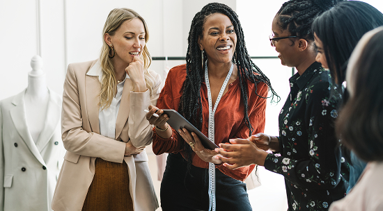 4 women reviewing a tablet and smiling